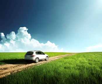 A white car driving in the middle of green grass.